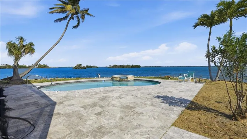 View of swimming pool with a pool with connected hot tub, a patio area, and a water view - Virtually Edited Image