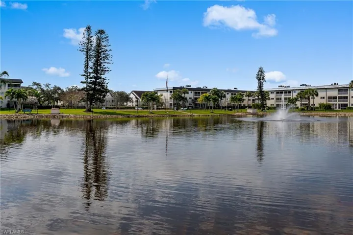 Waterfront property featuring a fountain, mature trees, and landscaping