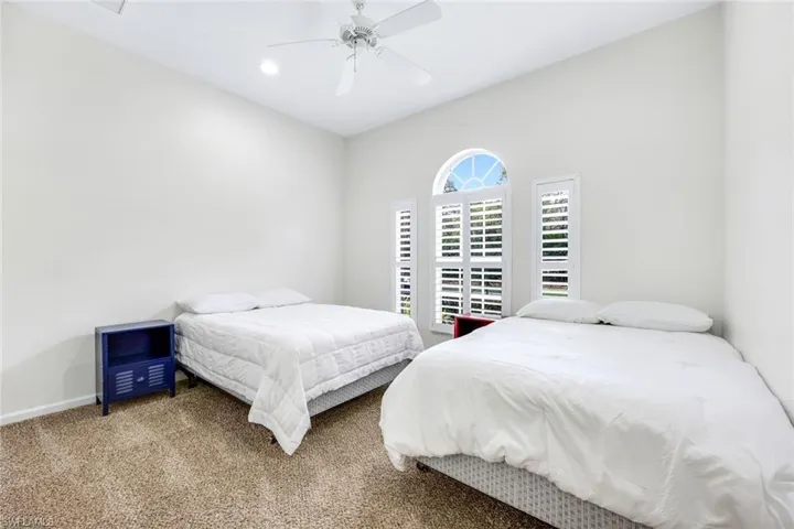 Carpeted bedroom featuring ceiling fan, a textured wall, and baseboards