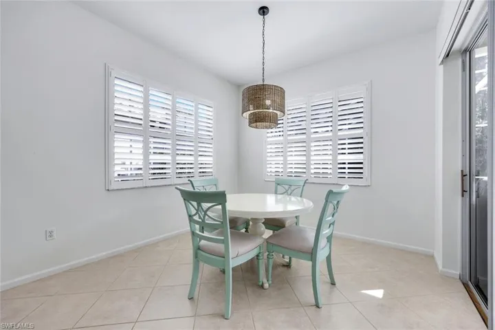 Dining area with baseboards, light tile patterned floors, and a notable chandelier