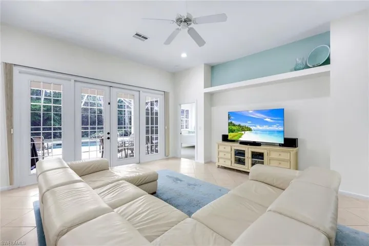 Living room with light tile patterned floors, visible vents, a ceiling fan, a sunroom, and baseboards