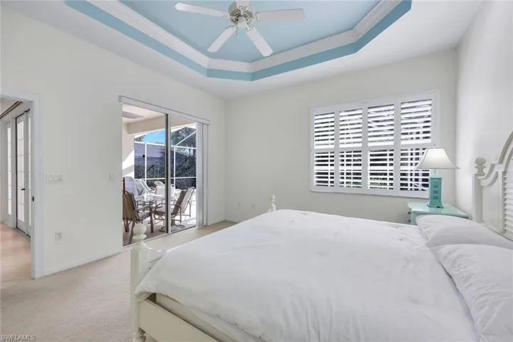 Carpeted bedroom featuring access to exterior, a raised ceiling, baseboards, and a ceiling fan