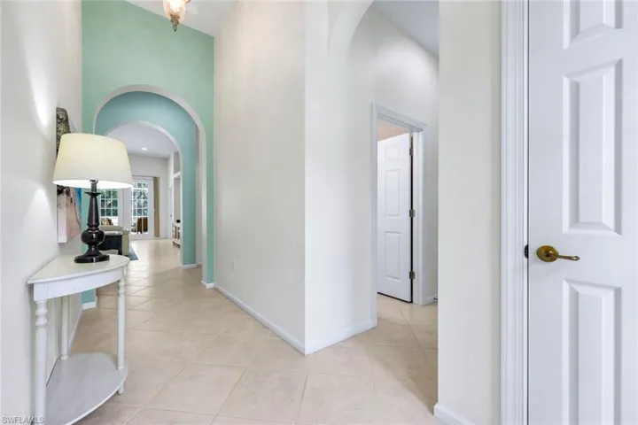 Corridor featuring light tile patterned floors, baseboards, and arched walkways