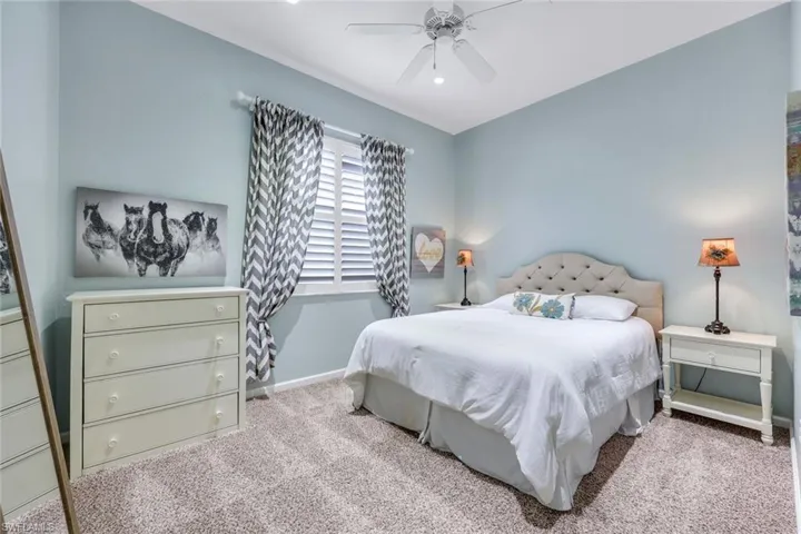 Carpeted bedroom with ceiling fan and baseboards