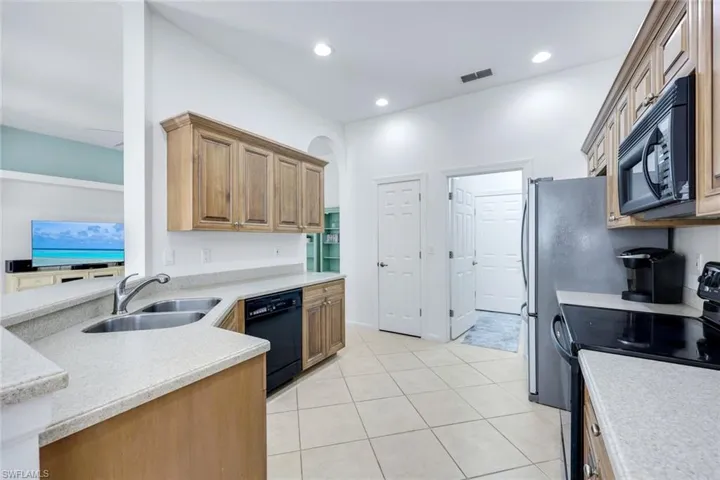 Kitchen featuring visible vents, light countertops, black appliances, a sink, and light tile patterned flooring