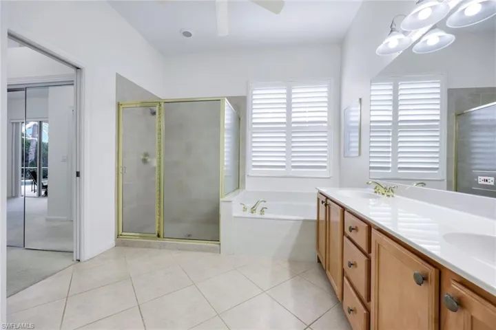 Bathroom with a stall shower, ceiling fan, a sink, and tile patterned floors