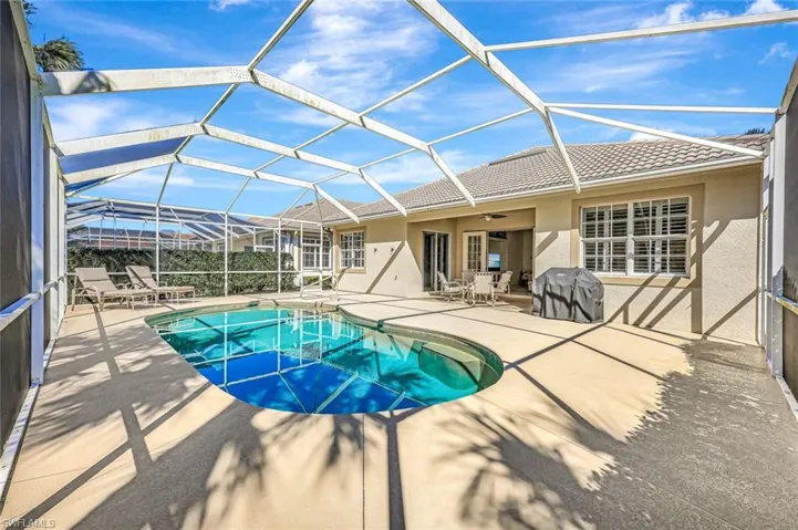 Pool with a ceiling fan, glass enclosure, a patio, and grilling area