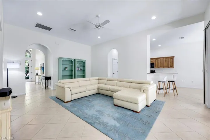 Living area with arched walkways, visible vents, and light tile patterned flooring
