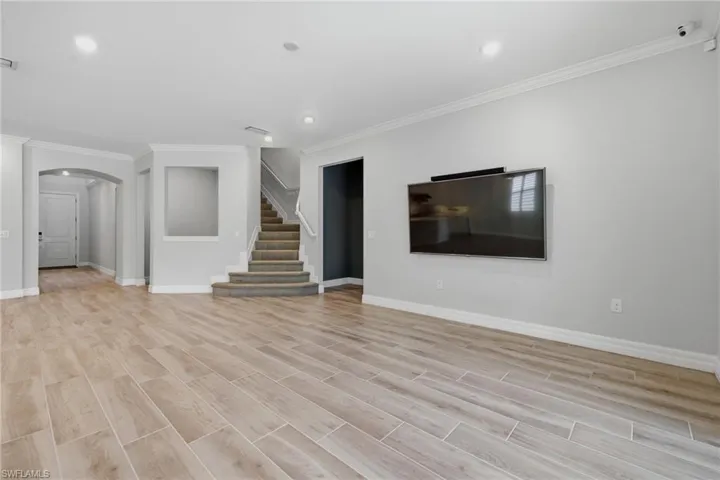 Spacious main living area featuring wood-finish tile flooring, recessed lighting, and crown molding