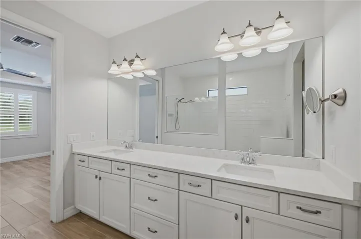Dual vanity with white cabinetry, light-toned countertops, and brushed nickel hardware