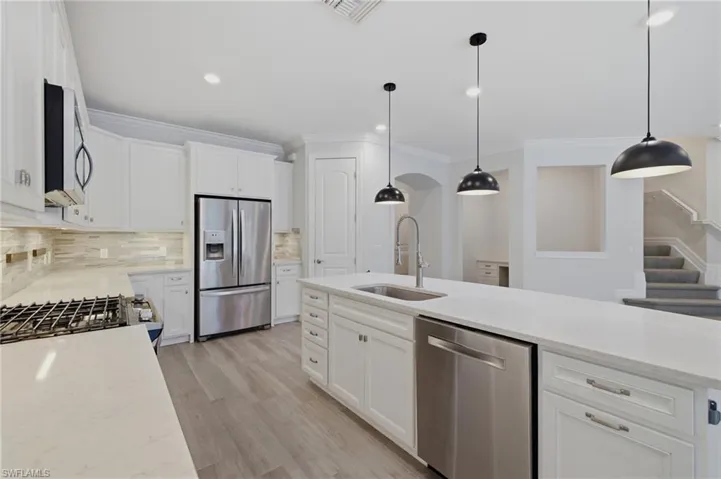 Modern kitchen featuring white cabinetry, light-toned countertops, stainless steel appliances, and a tile backsplash