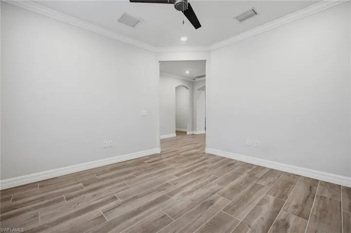 Spacious interior room featuring wood-finish flooring, crisp white walls, and a recessed lighting fixture