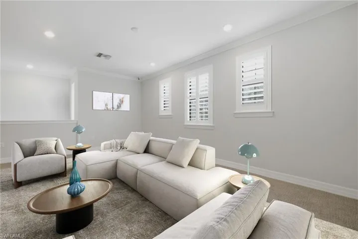 Bright living space featuring recessed lighting, crown molding, white plantation shutters, and a partial wall with a cap