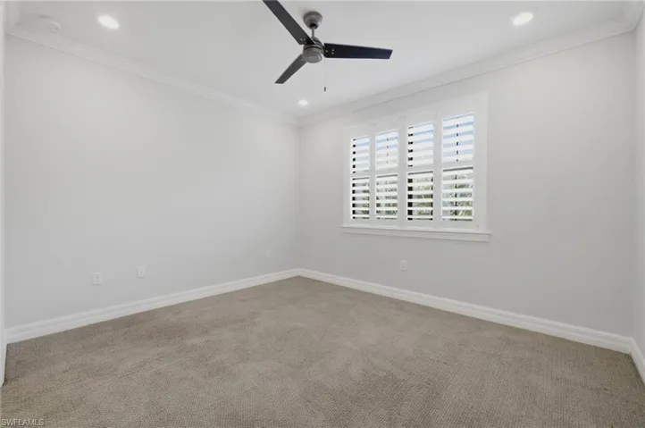 Carpeted room featuring a ceiling fan, recessed lighting, crown molding, and a window with plantation shutters