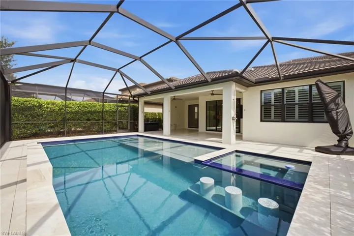 Screened pool enclosure featuring a rectangular pool with integrated spa and swim-up seating