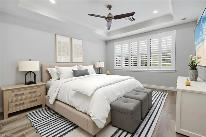 Spacious room featuring tray ceilings with recessed lighting, a modern ceiling fan, and wood-finish flooring