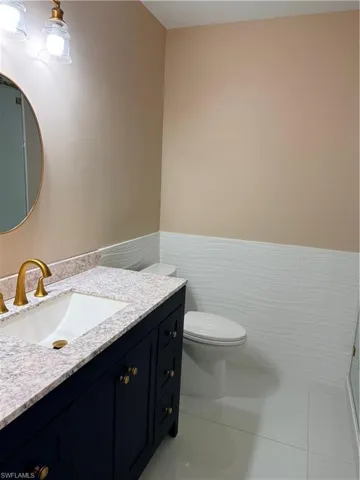 Guest Bathroom with vanity, tile walls, light tile patterned flooring, and wainscoting