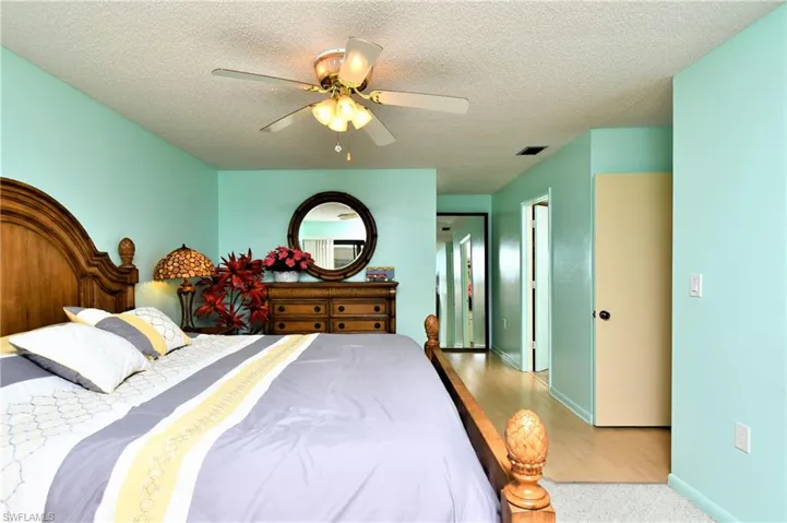 Bedroom with ceiling fan, a textured ceiling, and light wood-type flooring