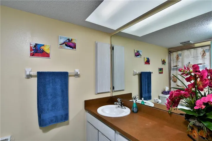 Bathroom with a textured ceiling, curtained shower, vanity, and toilet