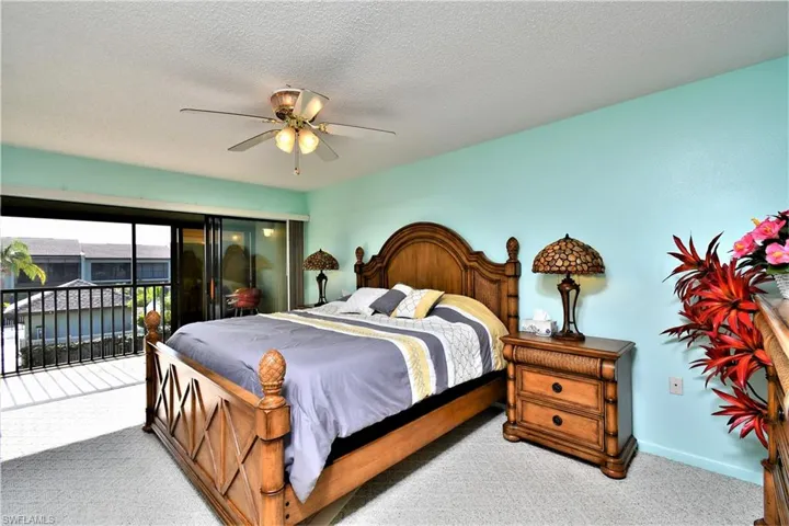 Bedroom with carpet, ceiling fan, access to outside, and a textured ceiling