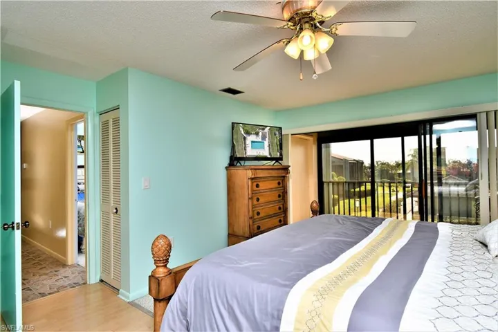 Bedroom with a closet, a textured ceiling, access to exterior, light hardwood / wood-style flooring, and ceiling fan