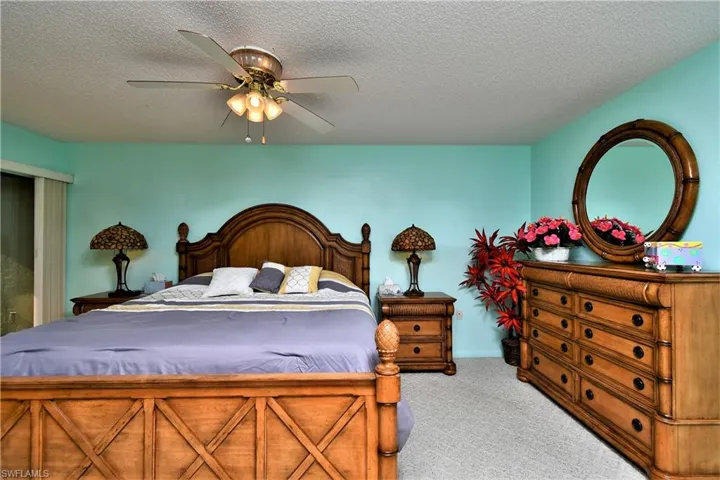 Bedroom with a textured ceiling, ceiling fan, and light colored carpet