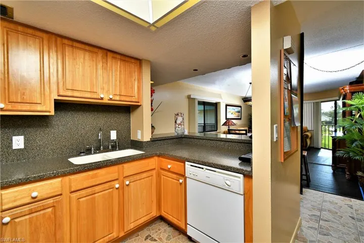 Kitchen with a textured ceiling, decorative backsplash, dishwasher, and sink