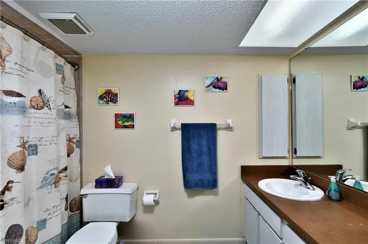 Bathroom with a textured ceiling, vanity, toilet, and a shower with curtain
