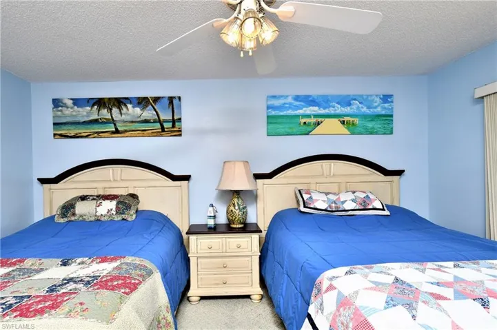 Carpeted bedroom with a textured ceiling and ceiling fan
