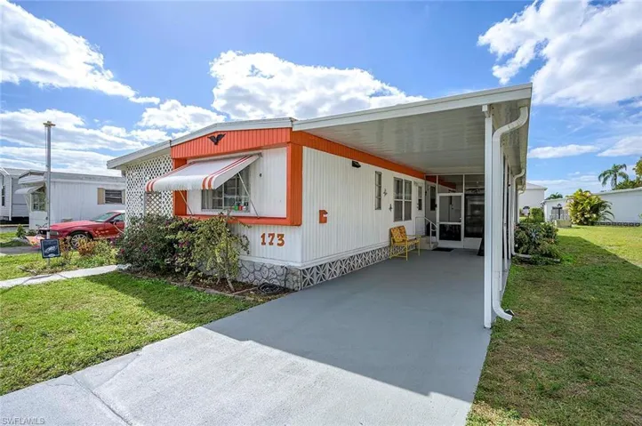 Manufactured / mobile home with driveway, a front yard, and a carport