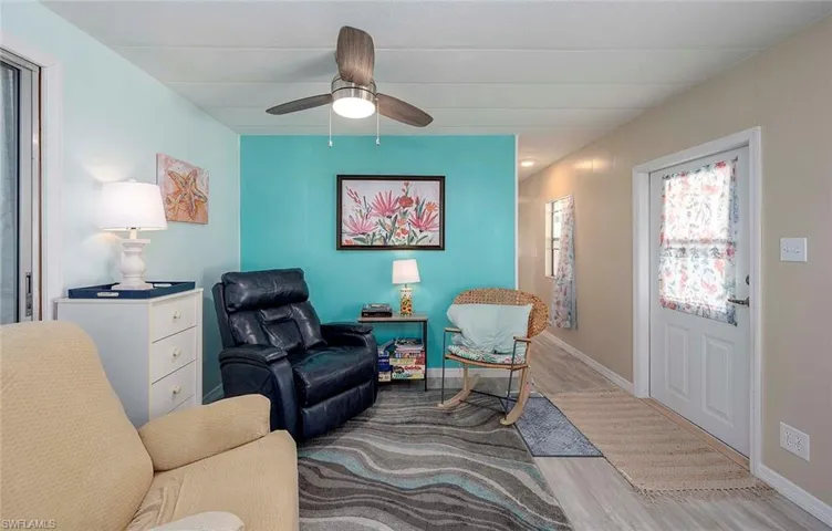 Sitting room featuring a ceiling fan, baseboards, and light wood-type flooring