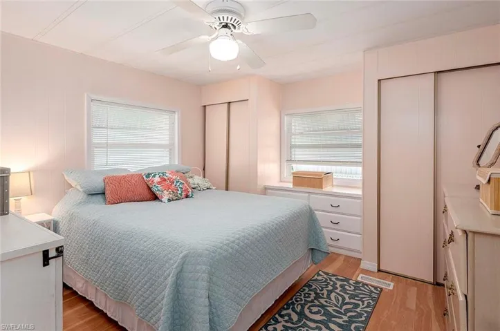 Bedroom featuring multiple closets, visible vents, light wood-style flooring, and ceiling fan