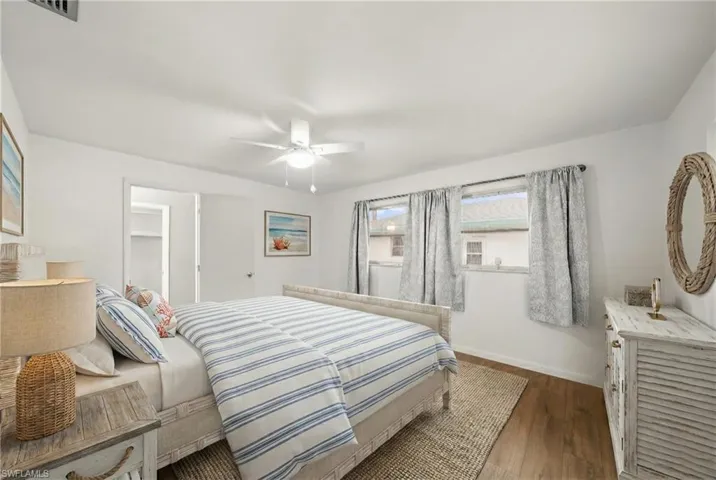 Bedroom with wood finished floors, ceiling fan, and a walk in closet