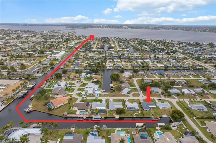 Aerial view of property and surrounding area featuring a nearby body of water and nearby suburban area