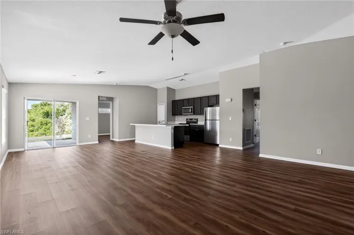 Open-concept living space featuring wood-finish flooring, a ceiling fan, and sliding glass doors providing access to the outdoors