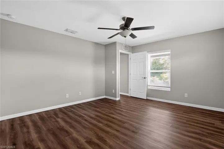 Spacious room featuring wood-finish flooring, light gray walls, and white baseboards