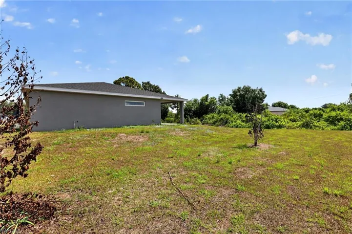 Expansive grassy yard area with a stucco exterior structure, featuring a single horizontal window