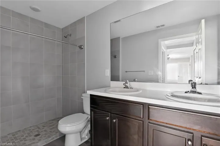 Bathroom featuring a dual-sink vanity with dark wood-finish cabinetry and a single-piece countertop