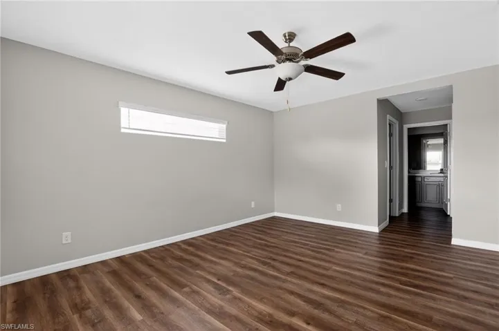 Spacious room featuring wood-finish flooring, light grey painted walls, and white baseboards