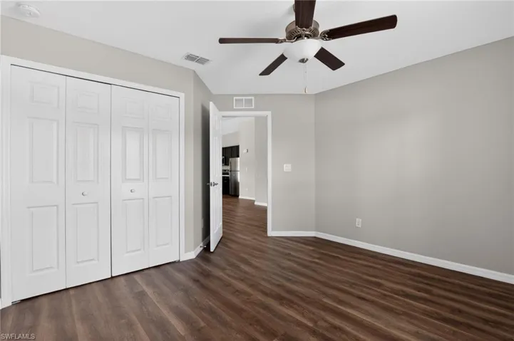Spacious room featuring wood-finish flooring, light grey walls, and white trim