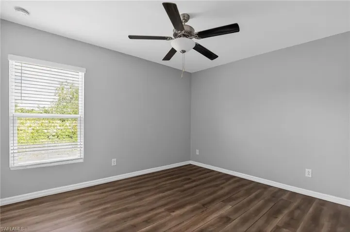 Spacious room featuring wood-finish flooring and a ceiling fan with integrated lighting