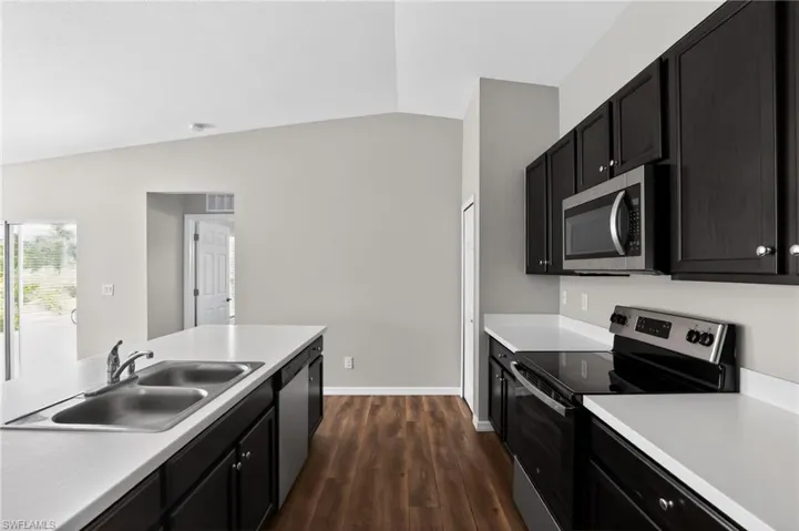 Modern kitchen featuring dark wood-finish cabinetry, white countertops, and wood-finish flooring