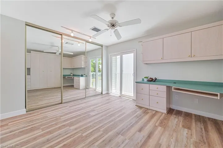 Unfurnished bedroom with built in desk, a closet, ceiling fan, and light hardwood / wood-style flooring