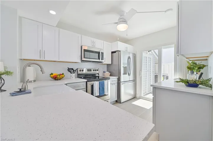 Kitchen featuring ceiling fan, stainless steel appliances, white cabinets, and sink
