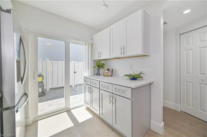 Kitchen with white cabinetry, light hardwood / wood-style floors, and stainless steel fridge with ice dispenser
