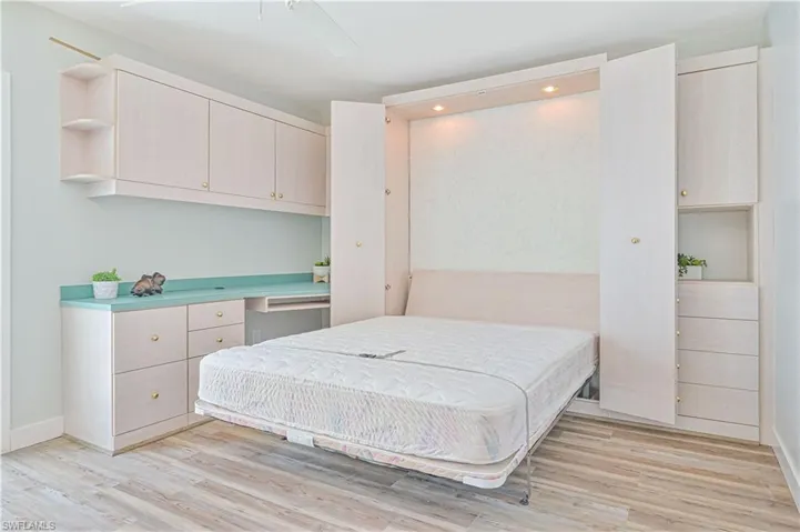 Bedroom with built in desk, ceiling fan, and light hardwood / wood-style flooring