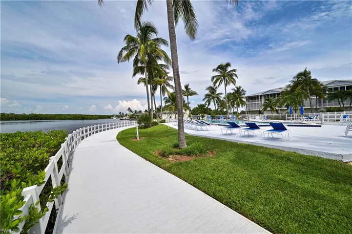 Surrounding community with a swimming pool, a lawn, and a water view