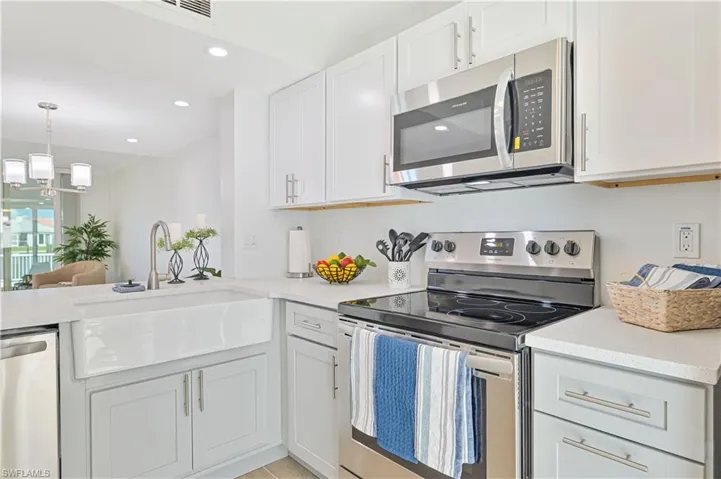 Kitchen with white cabinetry, stainless steel appliances, sink, and a chandelier