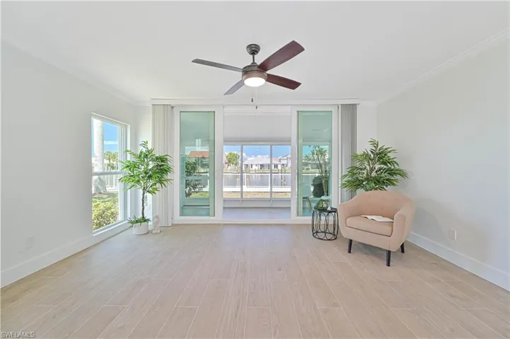 Living area with ceiling fan, light wood-type flooring, and crown molding