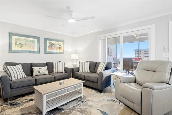 Living area with a ceiling fan, ornamental molding, and light wood-style floors